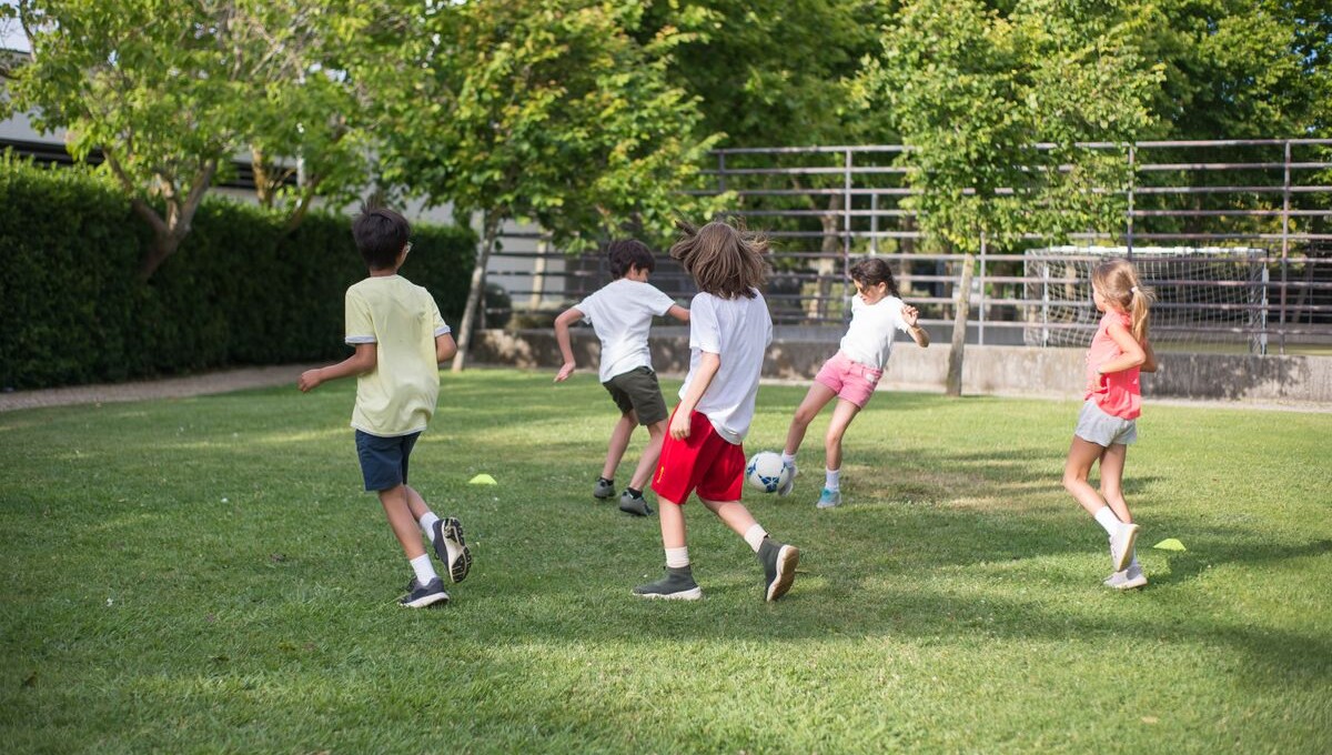 A group of kids playing a casual soccer game together on a grassy lawn